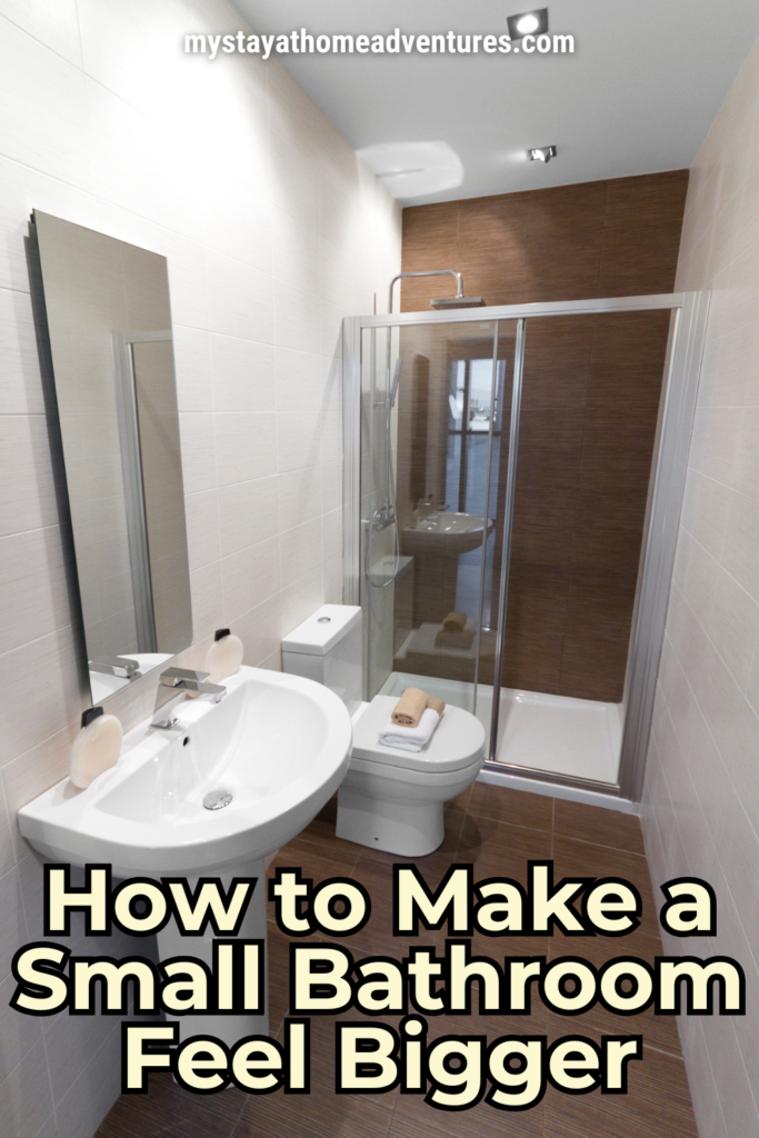 A narrow bathroom with a wall-mounted sink, a large mirror, a glass shower enclosure, and light-colored tiles, creating a spacious and airy feel.