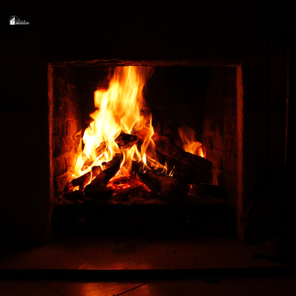 A roaring fire in a brick fireplace, casting a warm glow and providing heat for the home.