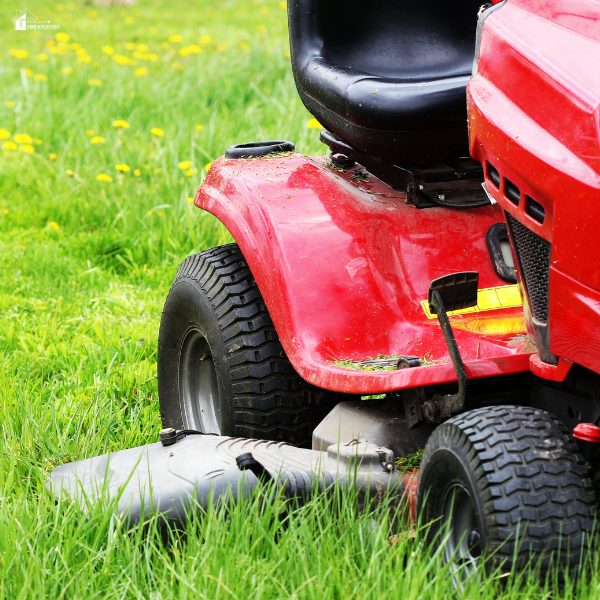 A red lawn tractor sits on tall grass, showing signs of recent mowing activity.