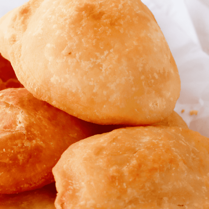 A close-up of freshly fried Puerto Rican arepas, showcasing their golden-brown, crispy exterior and fluffy texture, perfect for serving with stewed beans, picadillo, or melted butter.